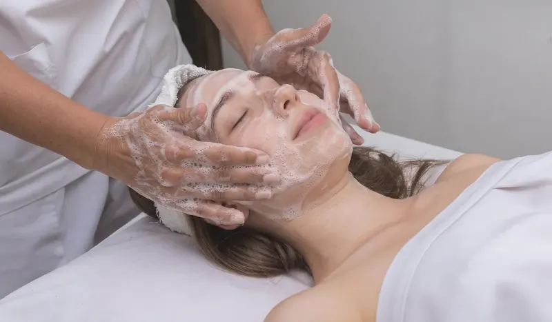 Esthetician massaging an oxygen bubble cleanse into a relaxed client's face