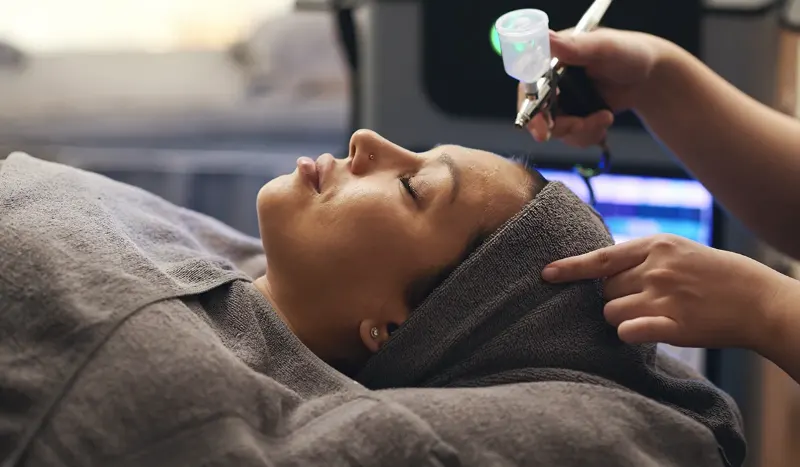 Technician spraying an oxygen infusion serum onto a client's face