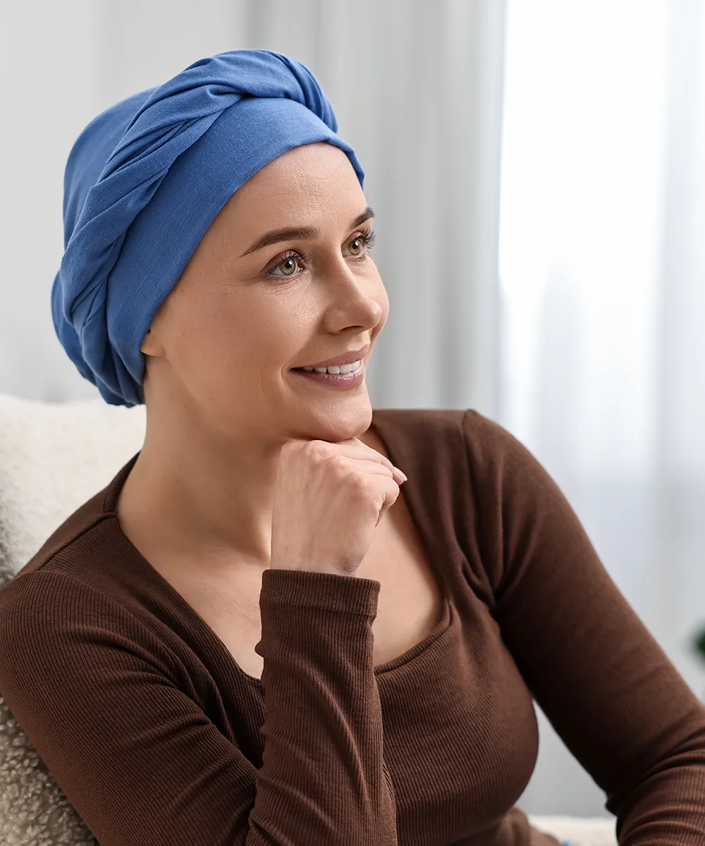 Smiling woman in a blue head wrap, resting her chin on her hand