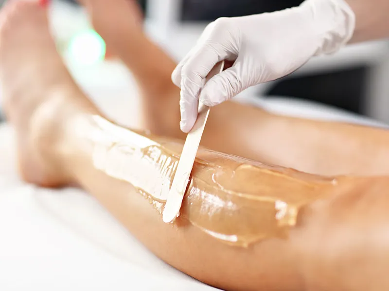 Warm wax applied to the leg during a hair removal service